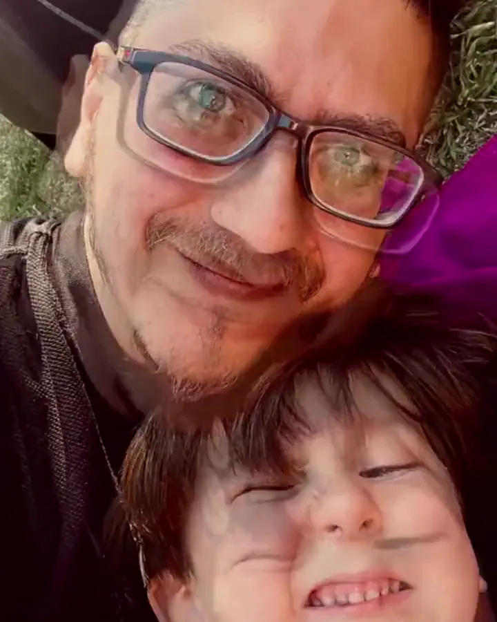 Jere y su hijo mejilla con mejilla, sonriendo, al aire libre.
