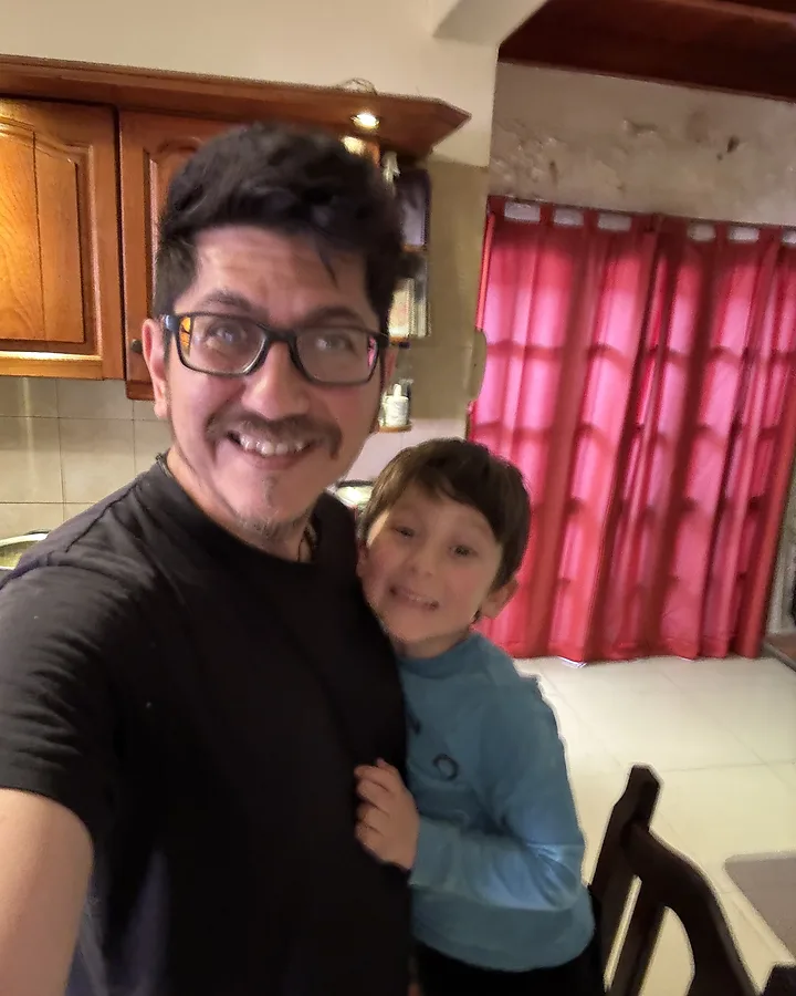 Jere y su hijo sonriendo, abrazados, en una cocina.